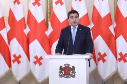 პოლიტიკოსი გამოსვლის დროს, ფონზე საქართველოს დროშები — საქართველო