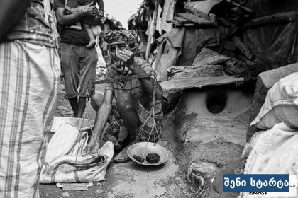 ადამიანი ბაზარში, რომელიც სასურსათო პროდუქტებს აწონებს — საქართველო