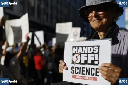 მიტინგზე ქალი პლაკატით - 'Hands Off Science!' — საქართველო