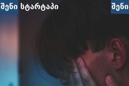 ახალგაზრდა ადამიანი ტელეფონზე, სახე ხელით დაფარული — საქართველო